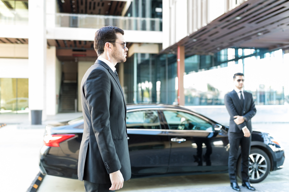 Executive protection agents standing by car while doing their duty in city
